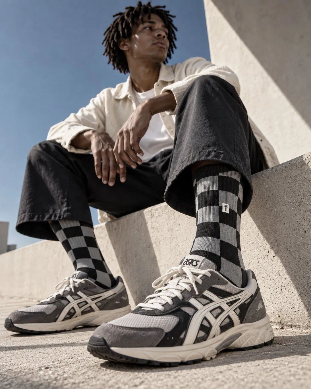 Black and grey checkered TAKIA crew socks worn with grey retro running sneakers
